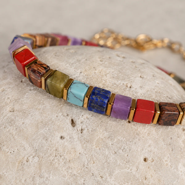 Close-up of 7 chakra cube beads showing red jasper, turquoise and lapis with gold hematite spacers