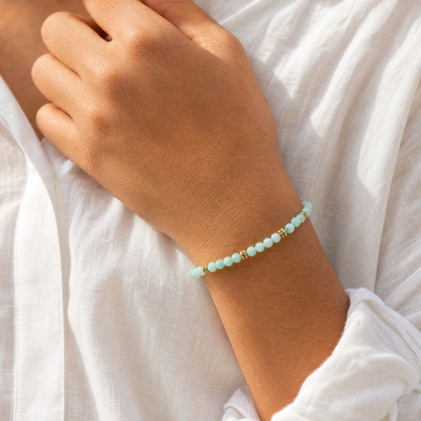 Woman wearing the Amazonite 4mm Bead Bracelet with Gold Spacers with a white linen shirt