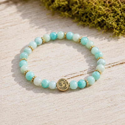 Soultheory Amazonite 4mm Bracelet with Om Charm on weathered oak beside moss