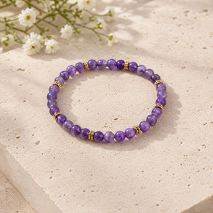 Soultheory Amethyst 4mm Bead Bracelet with Gold Spacers on a limestone plinth with jasmine