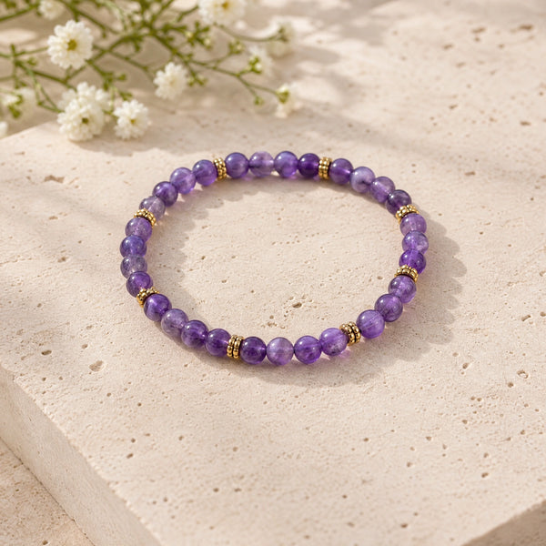 Soultheory Amethyst 4mm Bead Bracelet with Gold Spacers on a limestone plinth with jasmine