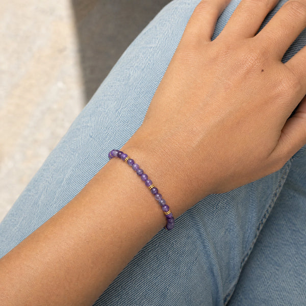 Woman wearing the Amethyst 4mm Bead Bracelet with Gold Spacers with blue denim