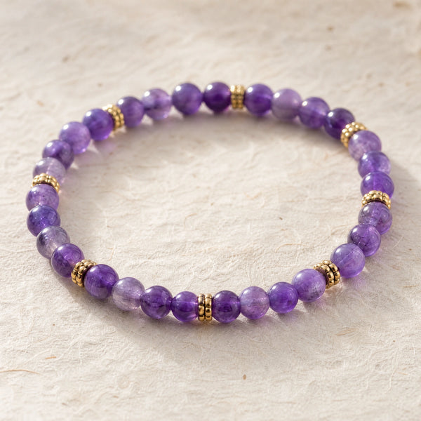 Close-up of the Amethyst 4mm Bead Bracelet with Gold Spacers on cream handmade paper
