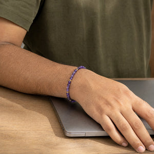 Man wearing the Amethyst bracelet, at a wooden desk
