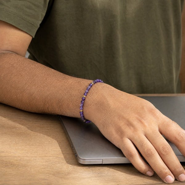 Man wearing the Amethyst bracelet, at a wooden desk