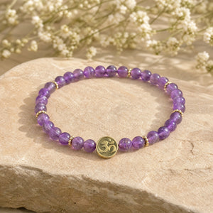 Soultheory Amethyst 4mm Bracelet with Om Charm on a sandstone block with white flowers