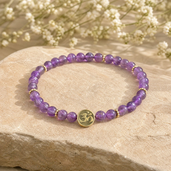 Soultheory Amethyst 4mm Bracelet with Om Charm on a sandstone block with white flowers