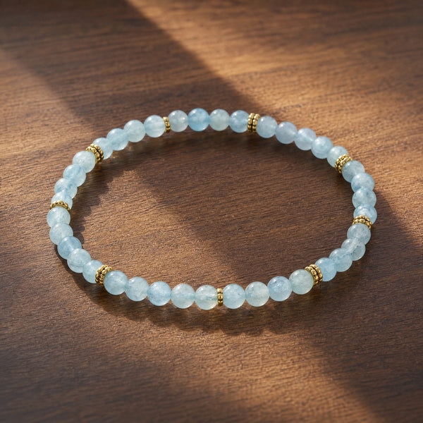 Soultheory Aquamarine 4mm Bead Bracelet with Gold Spacers on dark walnut wood