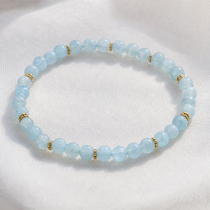 Close-up of the Aquamarine 4mm Bead Bracelet with Gold Spacers on white linen