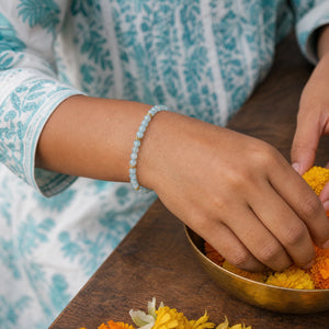 Woman wearing the Aquamarine bracelet, arranging marigold flowers