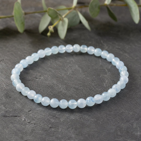 Soultheory Aquamarine 4mm Round Bead Bracelet on dark slate with eucalyptus
