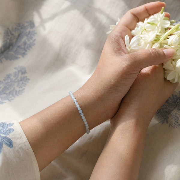 Woman wearing the Aquamarine bracelet, holding fresh jasmine flowers