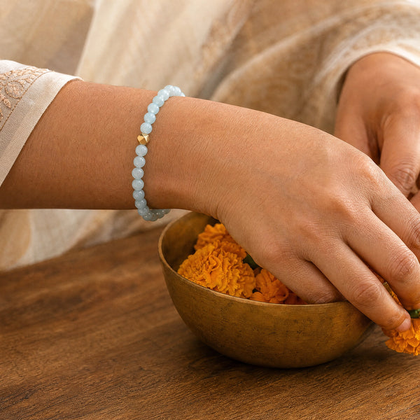 Woman wearing the Aquamarine bracelet, arranging marigold flowers