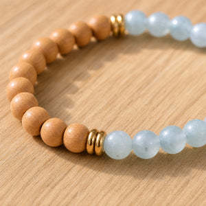 Close-up of the Aquamarine & Rosewood 6mm Bead Bracelet on a light oak board