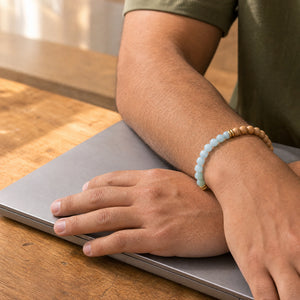 Man wearing the Aquamarine bracelet, at a wooden desk