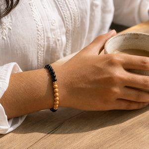 Woman wearing the Black Onyx bracelet, holding a ceramic coffee cup