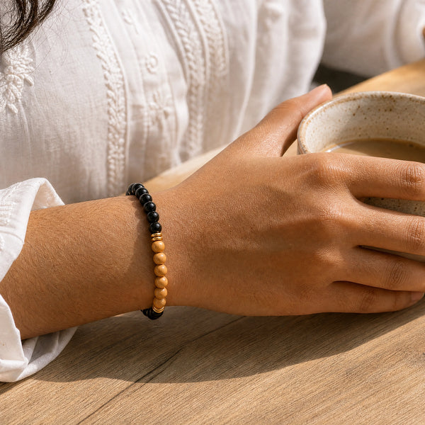 Woman wearing the Black Onyx bracelet, holding a ceramic coffee cup