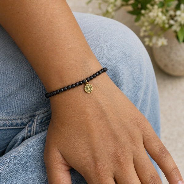Woman wearing the Black Tourmaline 4mm Bracelet with Om Charm with blue denim