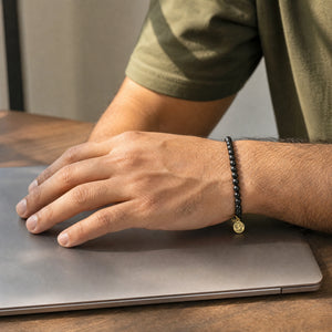 Man wearing the Black Tourmaline bracelet, at a wooden desk