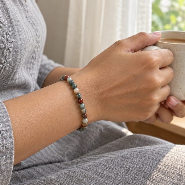 Woman wearing the Bloodstone bracelet, holding a mug of tea