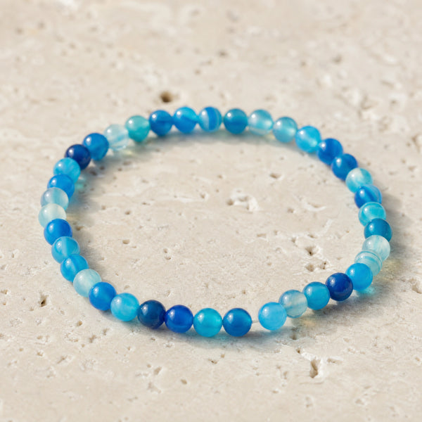 Close-up of the Blue Agate 4mm Round Bead Bracelet on pale travertine