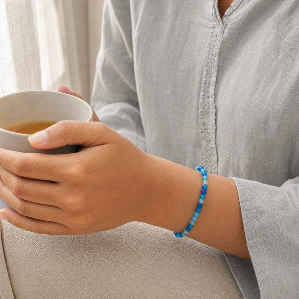 Woman wearing the Blue Agate bracelet, holding a mug of tea