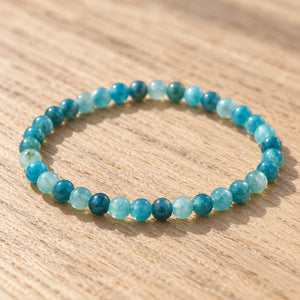 Close-up of the Blue Apatite 4mm Round Bead Bracelet on a light oak board