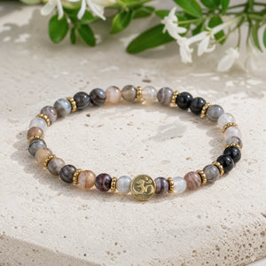Soultheory Botswana Agate 4mm Bracelet with Om Charm on a limestone plinth with jasmine