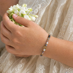 Woman wearing the Botswana Agate bracelet, holding fresh jasmine flowers