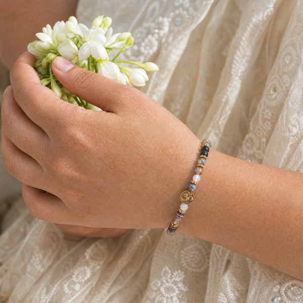 Woman wearing the Botswana Agate bracelet, holding fresh jasmine flowers