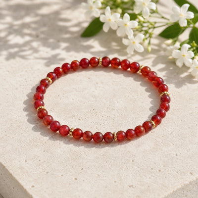 Soultheory Carnelian 4mm Bead Bracelet with Gold Spacers on a limestone plinth with jasmine