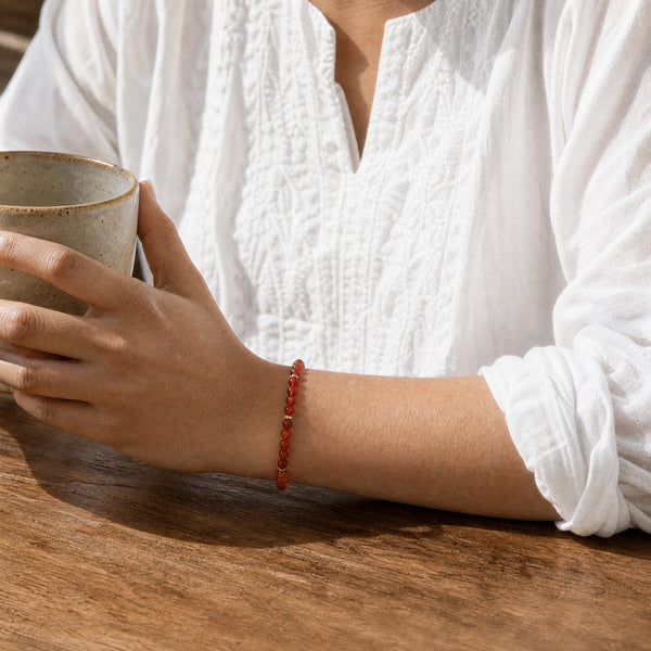 Woman wearing the Carnelian bracelet, holding a ceramic coffee cup