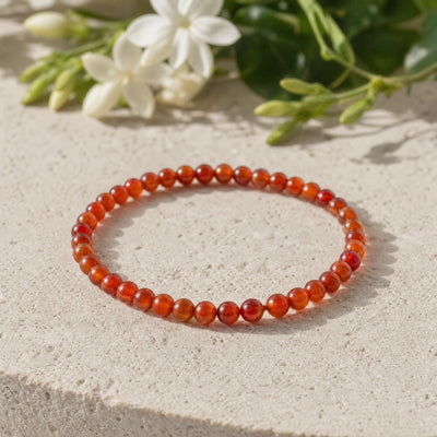 Soultheory Carnelian 4mm Round Bead Bracelet on a limestone plinth with jasmine
