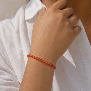 Woman wearing the Carnelian 4mm Round Bead Bracelet with a white linen shirt