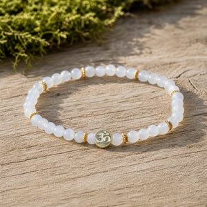 Soultheory Chalcedony 4mm Bracelet with Om Charm on weathered oak beside moss
