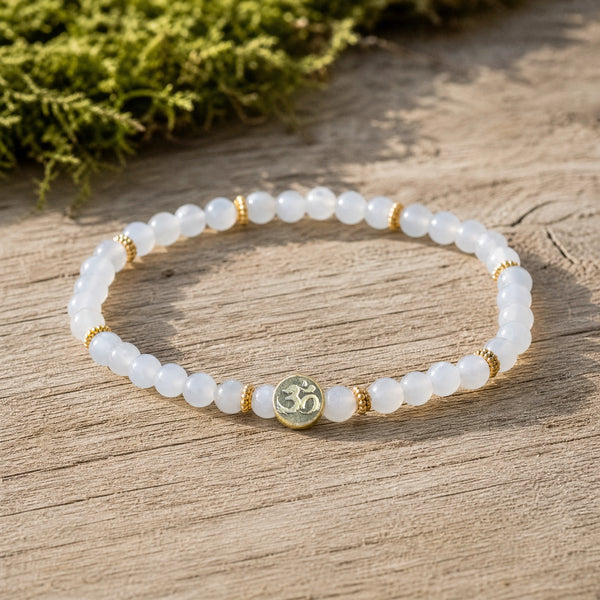Soultheory Chalcedony 4mm Bracelet with Om Charm on weathered oak beside moss