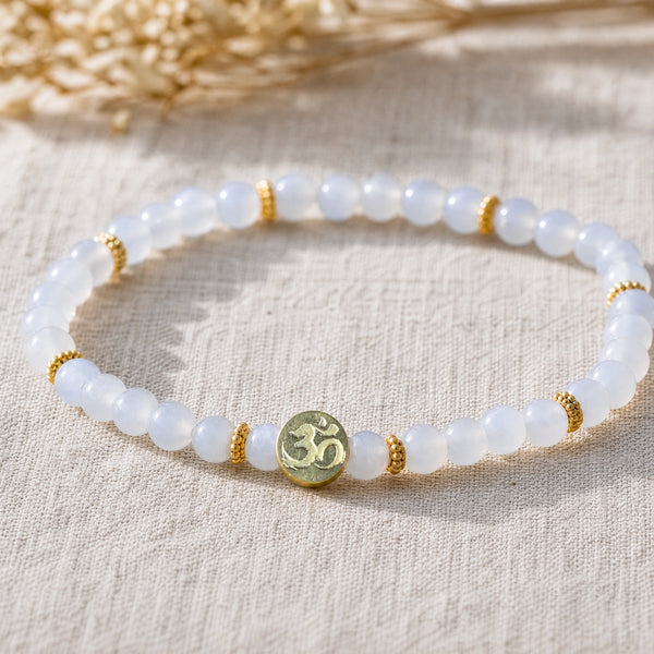 Close-up of the Chalcedony 4mm Bracelet with Om Charm on natural linen