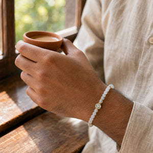 Man wearing the Chalcedony bracelet, holding a cup of chai