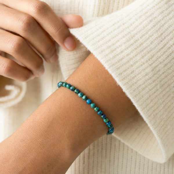 Woman wearing the Chrysocolla 4mm Round Bead Bracelet with a cream knit cardigan