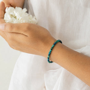 Woman wearing the Chrysocolla bracelet, holding fresh jasmine flowers