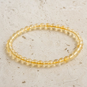 Close-up of the Citrine 4mm Round Bead Bracelet on pale travertine