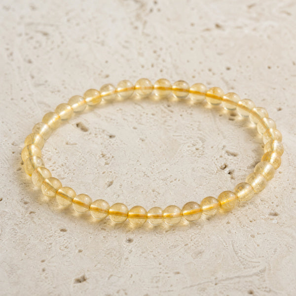 Close-up of the Citrine 4mm Round Bead Bracelet on pale travertine