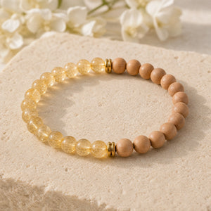 Soultheory Citrine & Rosewood 6mm Bead Bracelet on a sandstone block with white flowers