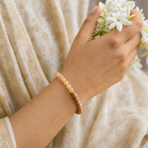 Woman wearing the Citrine bracelet, holding fresh jasmine flowers