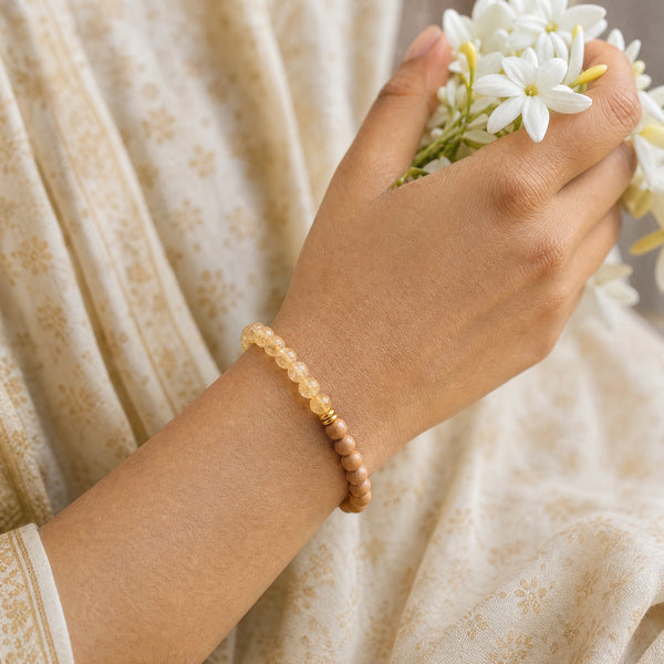Woman wearing the Citrine bracelet, holding fresh jasmine flowers