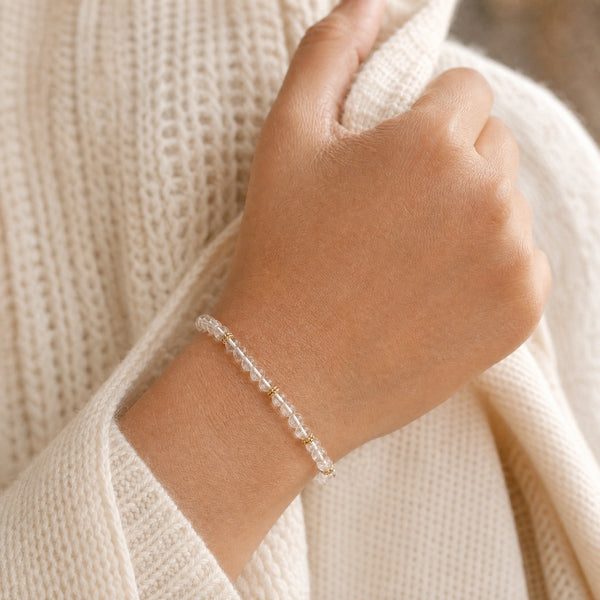 Woman wearing the Clear Quartz 4mm Bead Bracelet with Gold Spacers with a cream knit cardigan