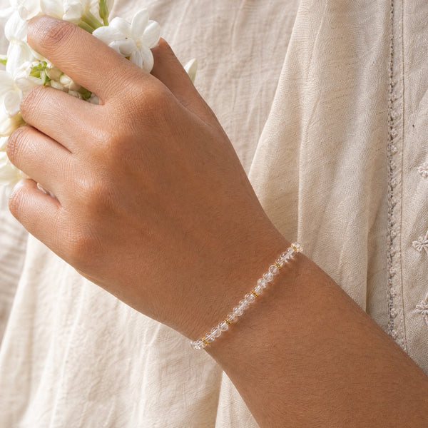 Woman wearing the Clear Quartz bracelet, holding fresh jasmine flowers