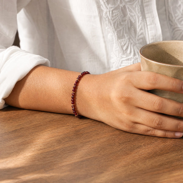 Woman wearing the Garnet bracelet, holding a ceramic coffee cup
