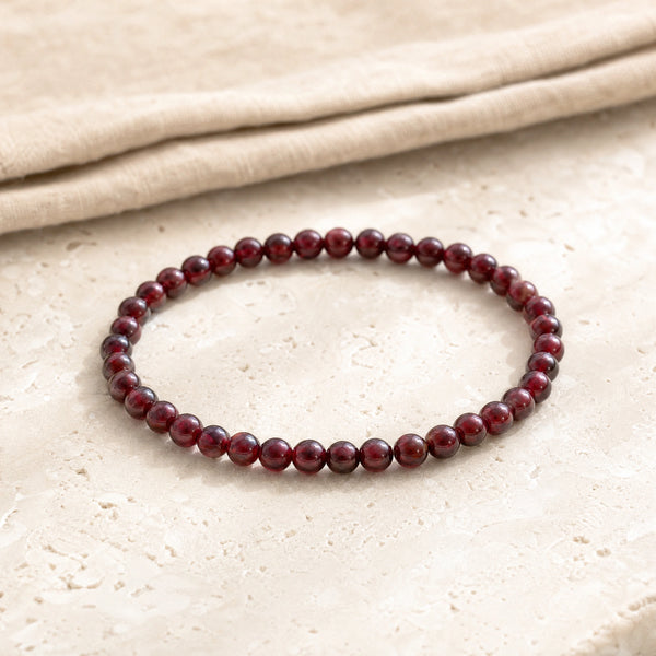 Soultheory Garnet 4mm Round Bead Bracelet on a travertine slab and linen