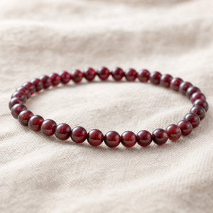 Close-up of the Garnet 4mm Round Bead Bracelet on natural linen